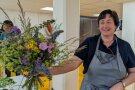 Frau hält einen bunten Blumenstrauß in der Hand und lächelt