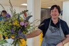 Frau hält einen bunten Blumenstrauß in der Hand und lächelt