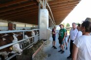 Der Landwirt steht mit den Studierenden vor seinem Bullenmaststall und erklärt, dass er möglichst einfach und günstig gebaut hat. 