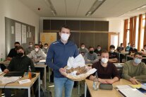 Mann steht mit Brotkorb vor Klasse