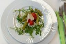Ein Teller mit Spargelsalat aus Erdbeeren, Rucola und Parmesan.