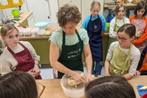 Kinder und eine Lehrkraft stehen vor einem Tisch mit Brot und Gemüse-Käse-Spießen. Foto © Pia Orthen