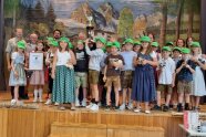 Kinder stehen auf einer Bühne und halten Kuscheltiere in den Händen und auch eine Pokal