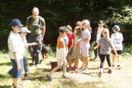 EIn Gruppe Kinder und ein Mann mit Hund stehen in einer Waldlichtung.