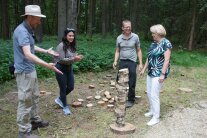 4 Menschen stehen um eine Turm aus Birkenscheiben