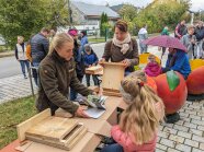 Kinder und Erwachsene stehen um einen Infotisch und bauen mit Holzteilen Fledermauskästen.