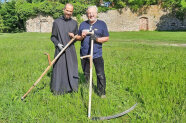 Frater David und Sensenlehrer Georg Hahn stehen mit ihrer Sense in einer Wiese.