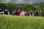 Kinder und Erlebnisbäuerin Stephanie Stahl stehen in einem grünen Gerstenfeld.