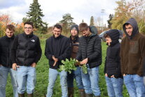 Eine Gruppe junger Männer steht auf einem Feld, einer hält eine Frucht in Händen.
