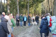 Personengruppe mit Referentin im Kreis stehend vor Waldstück.