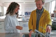 2 Frauen stehen in Küche vor Wasserhahn